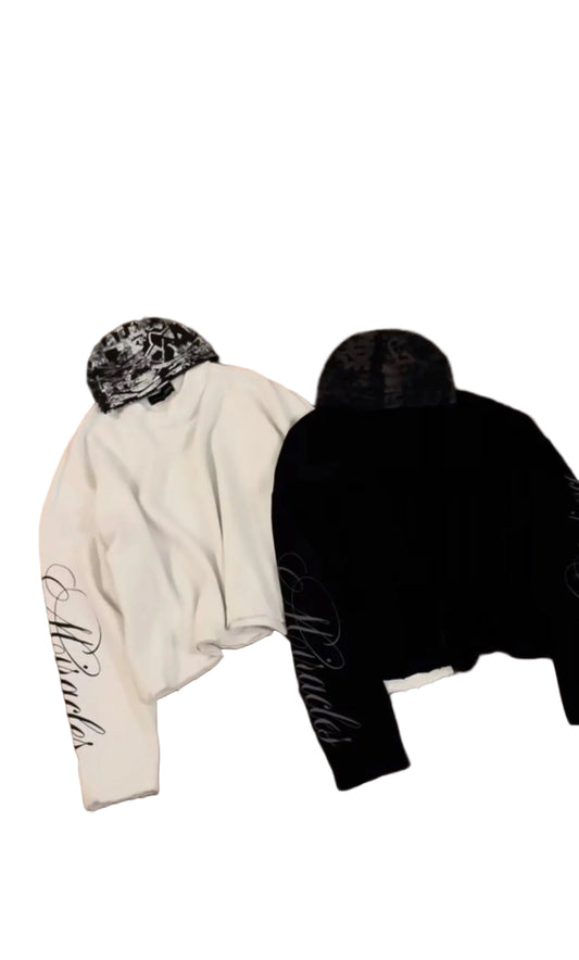 Two hoodies, one white and one black, with text on a wooden floor.